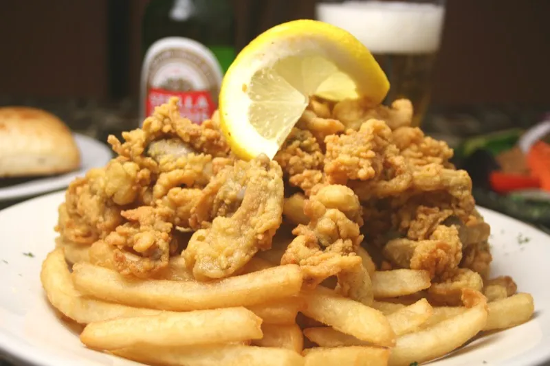 Native fried clams with fries and a lemon wedge