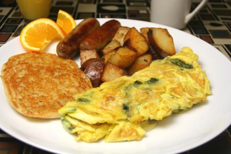 Spinach omelet with home fries, sausage and a potato pancake
