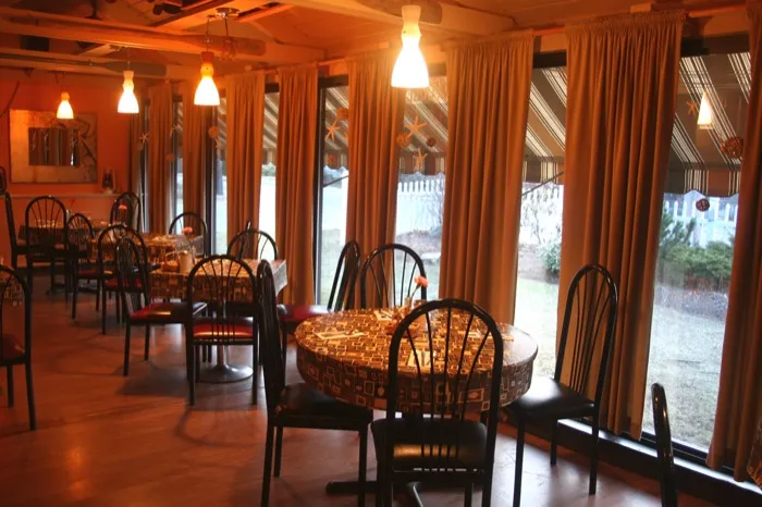 Dining room with drapes, pendant lights and tables by tall windows