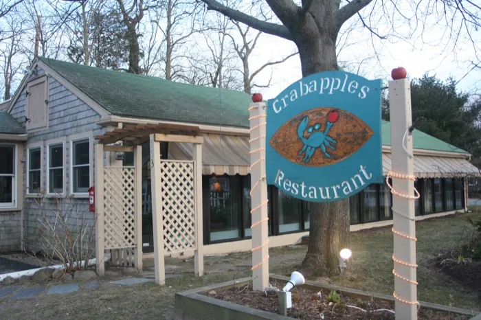 Crabapples sign hanging from a tree in front of the restaurant