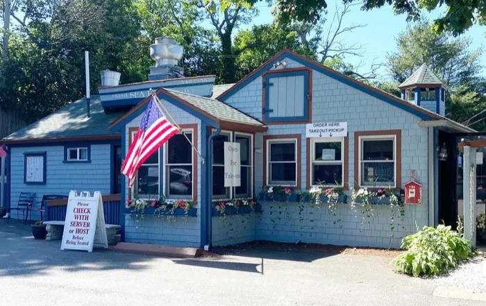 Crabapples storefront, a blue cottage with an American flag and flower boxes